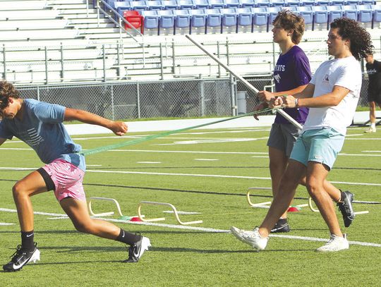 Paolo Garza holds bands that are around Noah Luckie's waist as he runs while Landon Griffith completes running over tiny obstacles while holding a pipe over his head. Photos by Jennifer Fierro/TexasChalkTalk.com