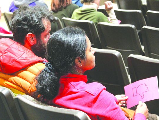 Marco and Vasavi Amara Olson demonstrated their opposition with a small sign among a large audience at a meeting about a proposed rock quarry. Raymond V. Whelan/The Highlander