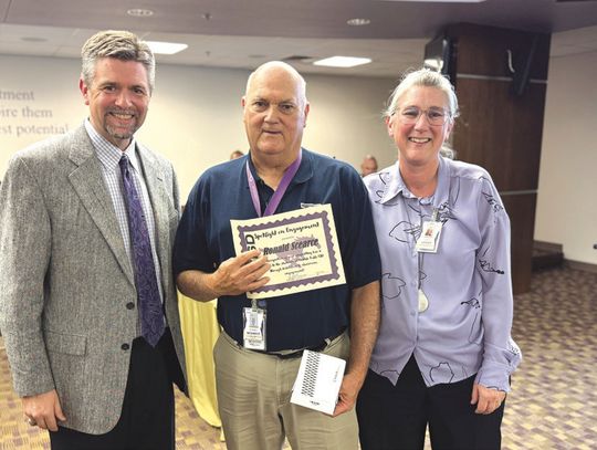 Coach Ronnie Scearce, with Superintendent Jeff Gasaway at his right and Assistant Superintendent of Curriculum and Instruction Yarda Leflet at his left, was presented with the Spotlight on Engagement Award for his decades of service and commitment to students.