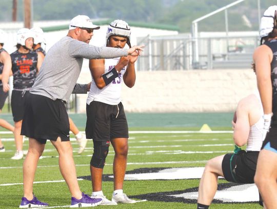 Head coach Keri Timmerman (left) tells senior quarterback Atreyu Machacek what he is seeing in the middle of the field.