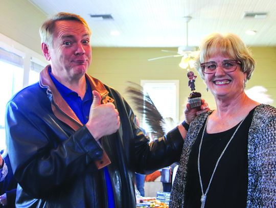 Seth Smith shows thumbs up with his right hand and holds a cupcake in his left hand to help Debbie Bindseil celebrate her upcoming retirement during a celebration Jan. 11 at the Spicewood Community Center.