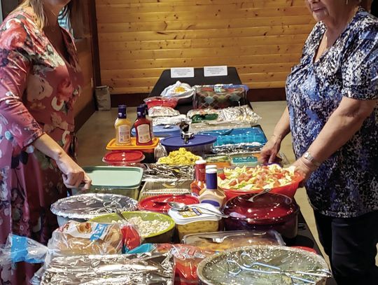Event organizer (left) Teresa Gray, Grissom Insurance, joins Hafdis Gentry, volunteer, to sort the potluck buffet.