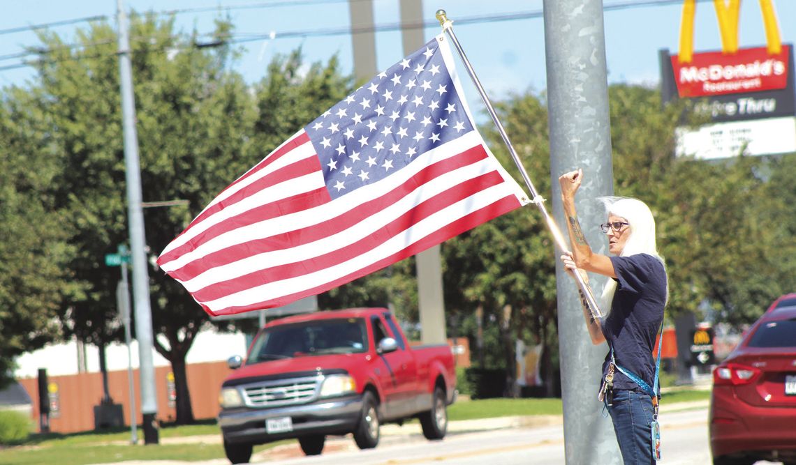 Burnet County resident Laura Silveia raises her arm to encourage the deafening sound of horns as multiple numbers of vehicles motored through the Texas 29 and U.S. 281 intersection Sept. 11. Silveia and 30 others commemorated Patriot Day at the intersection. Photos by Raymond V. Whelan/The...