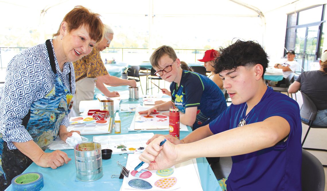 Timothy Salinas (right) concentrated on creating an artistic effect April 12 at Family Art Day, during the 2025 Paint the Town Art Festival. Volunteer Lynn Erickson and participant Zaiden Smith admired his work. Photos by Connie Swinney/The Highlander