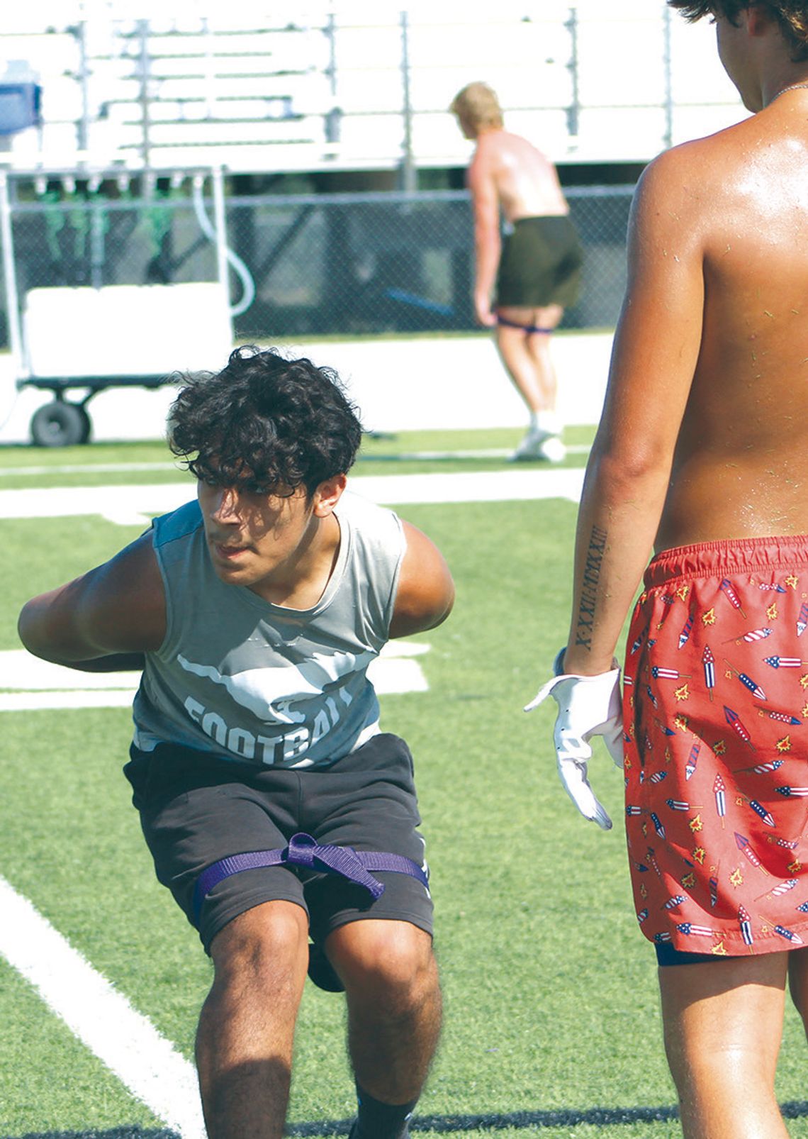 Bentley Trejo uses a band to keep his upper body in place as he runs backwards with his hands behind his back during a defensive back drill.