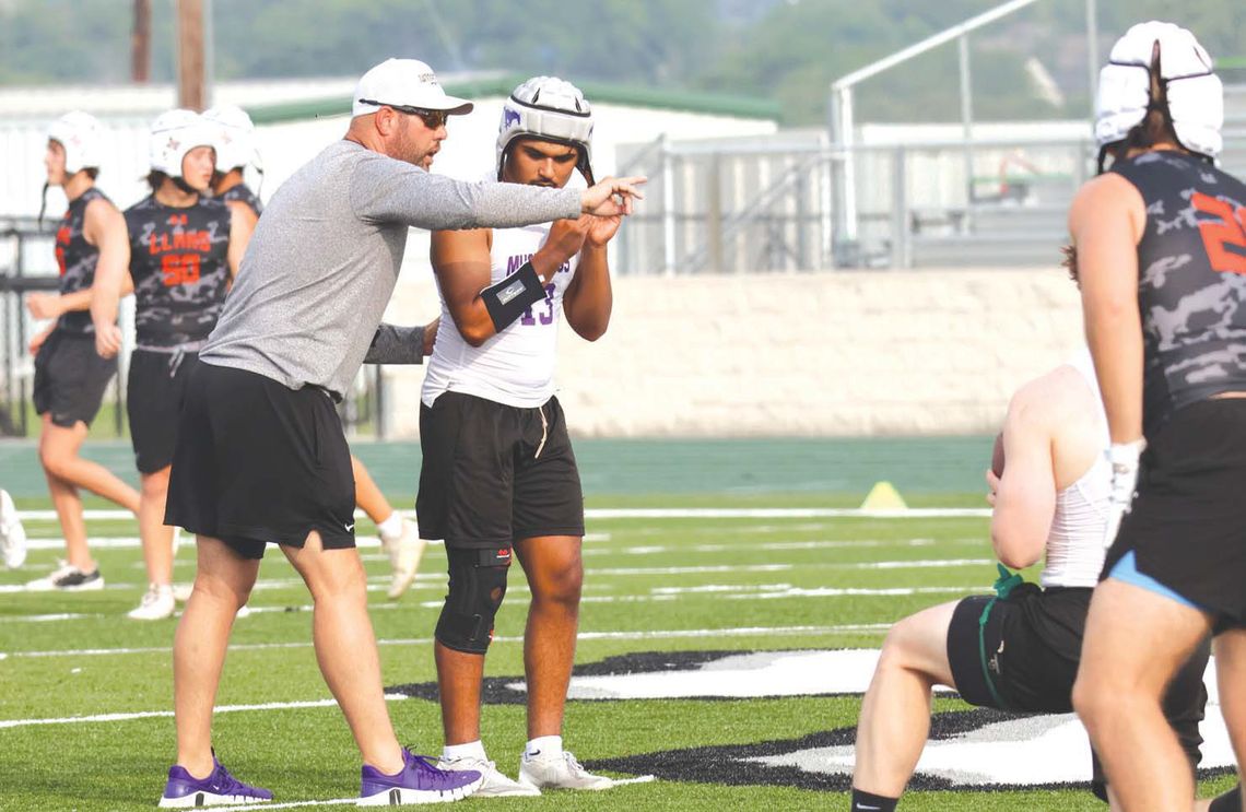 Head coach Keri Timmerman (left) tells senior quarterback Atreyu Machacek what he is seeing in the middle of the field.