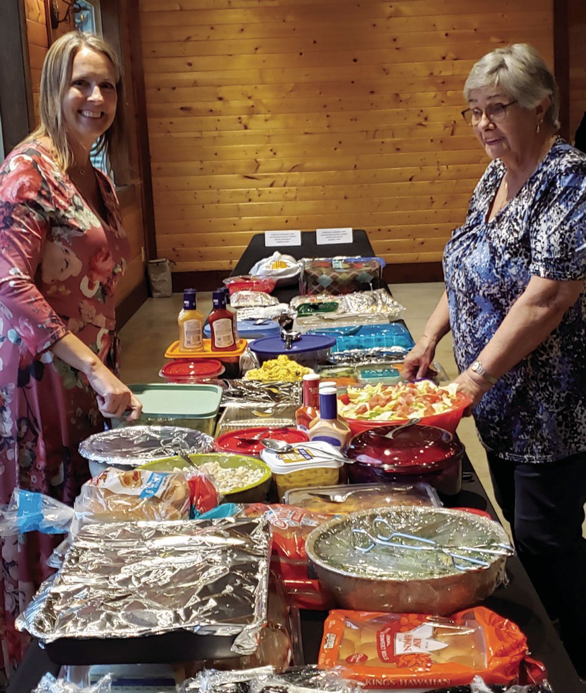 Event organizer (left) Teresa Gray, Grissom Insurance, joins Hafdis Gentry, volunteer, to sort the potluck buffet.