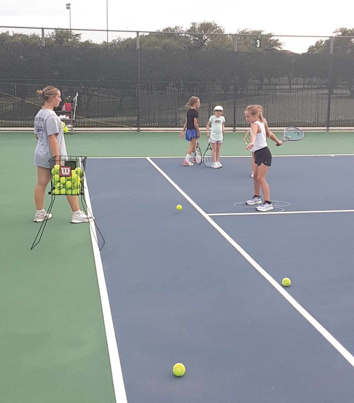 High school player Chloe Taylor (left) is dropping balls to June Williams, while Carter Cauble (back) and Brynlee Crouse wait their turn. Contributed photos